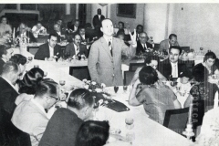 Cesar Salgado em mesa com pessoas e homem em pé