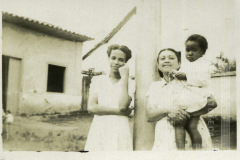 Mulheres de vestido claro com criança de colo