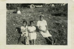 Crianças e mulher sentada na grama