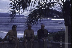 Três homens com mar ao fundo