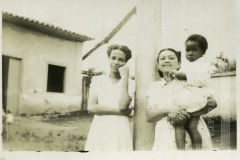 Mulheres de vestido claro com criança de colo